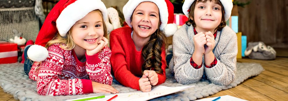 trois fillettes avec bonnets de père Noël avec des grands sourires