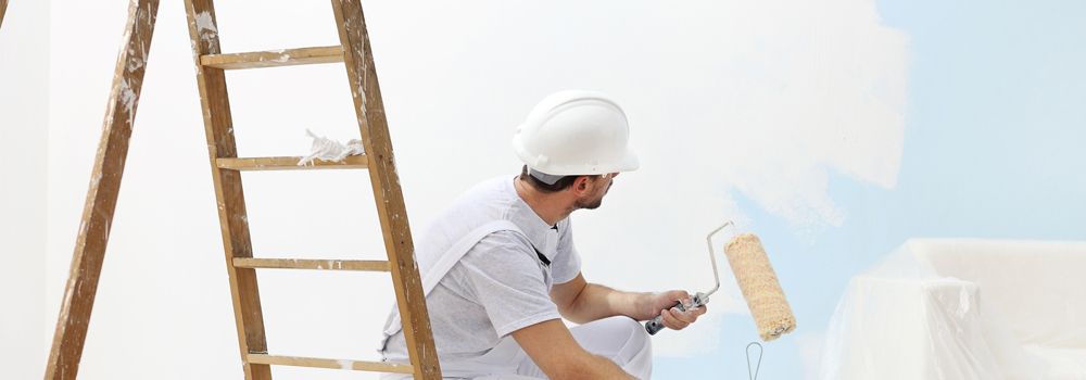 escabeau, homme avec casque de chantier en train de peindre le mur