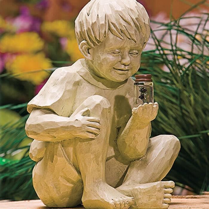 Un enfant tenant une statue de jardin luciole statue de garçon en pot de résine, en plein air dans la cour