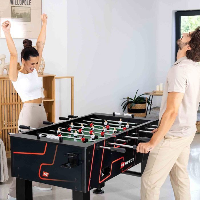 HOP-SPORT® Table de Baby-Foot Evolution, Table de Football pour Enfants et Adultes, avec 2 balles, 2 Porte-Boissons, 2 compteurs de buts, Massif et antidérapant, avec Pieds Ajustables, Noir