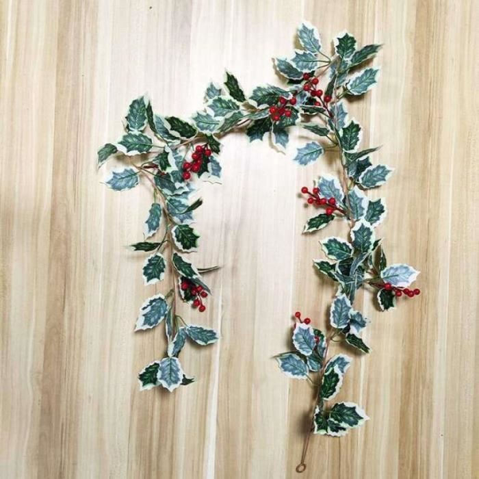 Couronne de Noël : grandes feuilles persistantes, baies de houx rouges et pommes de pin - France